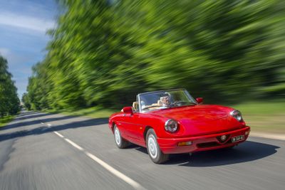 the red sports car is driving down the road near the trees