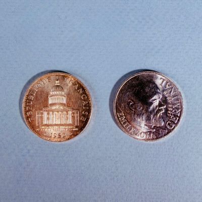 deux pièces de monnaie placées l'une à côté de l'autre sur une surface bleue