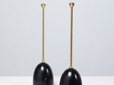 une paire de bougies noires et dorées posées sur une table blanche
