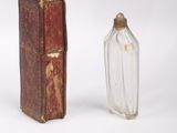 a small glass bottle next to a book on a white surface