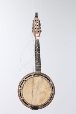 an old banjo is hanging from a string on a white wall