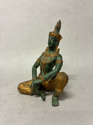 statue représentant une personne assise sur un morceau de bois, coiffée d'un chapeau