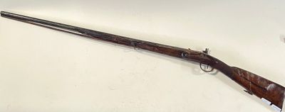 un vieux fusil avec une poignée en bois sur une surface blanche