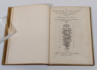 un livre ouvert posé sur une table blanche, à côté d'un verre