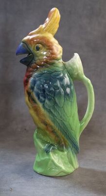 un oiseau en céramique perché sur le goulot d'un pichet