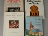 three books on a table with a clock and a church in the background