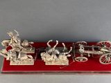 two silver figurines of a horse drawn carriage and a man on a horse drawn carriage