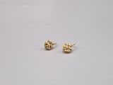 une paire de petites boucles d'oreilles en or sur une surface blanche