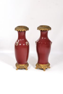 paire de vases rouges avec des bordures et des anses dorées sur fond blanc