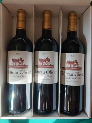 trois bouteilles de vin rouge dans une boîte blanche posée sur une table