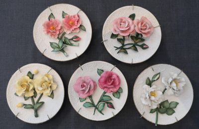 quatre assiettes blanches ornées de fleurs roses et jaunes, posées sur une table