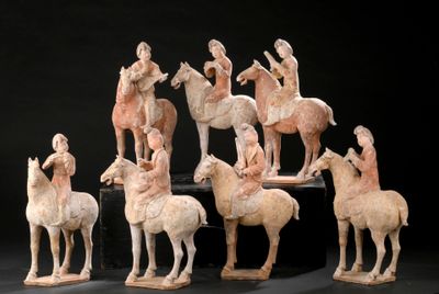 several figurines of people riding horses and horses on a black surface