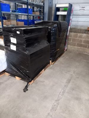 de nombreuses boîtes noires empilées sur des palettes dans un entrepôt