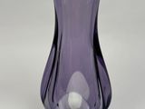un vase en verre violet posé sur une table blanche, sur fond blanc