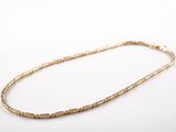 a close up of a gold necklace on a white surface