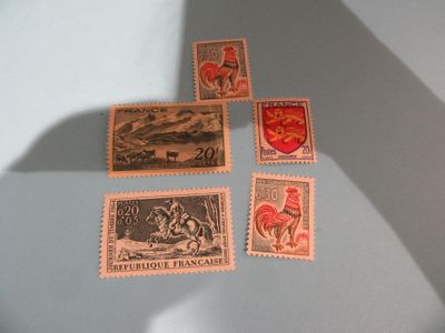 quatre timbres posés sur une table, avec l'ombre d'une personne tenant un couteau