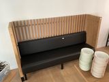 a black bench in a room with a wooden wall behind it