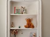 une étagère blanche sur laquelle sont posés un ours en peluche et des livres