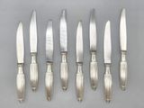 six silverplated knives and a knife holder on a table