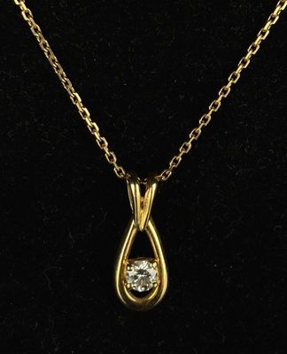 a gold necklace with a diamond on a black background