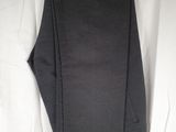 a pair of black pants hanging on a hanger on a white wall