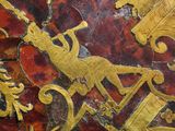a close up of a red and gold vase with gold designs