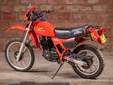 a red dirt bike parked in front of a brick wall