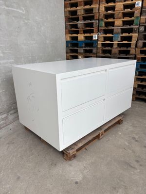 a close up of a white chest of drawers in a warehouse