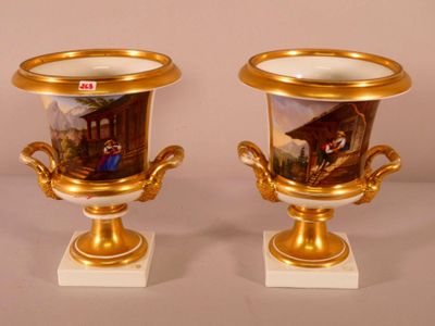 two gold vases with paintings on them sitting on a table