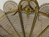 a gold metal fan with intricate designs on the top of it