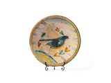 une assiette sur laquelle est peint un oiseau, posée sur un socle