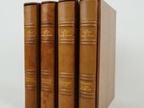 trois livres bruns posés l'un sur l'autre sur une surface blanche