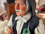 a figurine of an old man holding a pot and a teapot