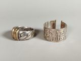 two silver rings on a white surface, one with a gold band and the other with a silver band