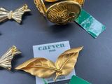 several pieces of gold leaf brooches and a tag on a table
