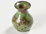 a small green vase sitting on a white surface