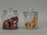 two glass jars with shells inside of them on a table