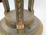 une horloge dorée et argentée posée sur un socle, sur une surface blanche