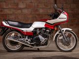 a red and white motorcycle parked in front of a brick wall