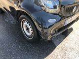 a small black smart car parked in a parking lot