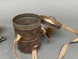 a small metal bucket with a strap around it and a pair of glasses next to it