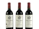 trois bouteilles de vin rouge posées l'une à côté de l'autre sur une surface blanche