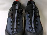 une paire de chaussures de randonnée noires avec des lacets orange sur un fond blanc