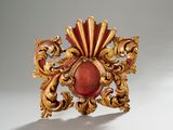une broche rouge et dorée sur un fond blanc