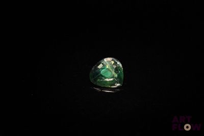 a close up of a green and white diamond on a black surface