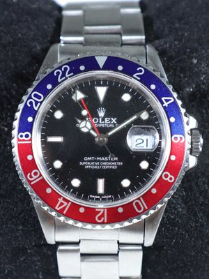 une photo d'une montre Rolex avec une lunette rouge et bleue