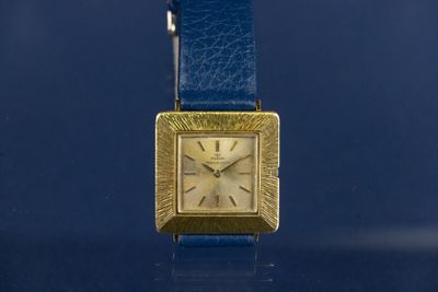 a gold watch with a blue strap around it