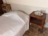 un lit recouvert d'une couverture blanche et une petite table sur laquelle se trouve un bol