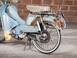 a blue moped that is parked in front of a brick wall