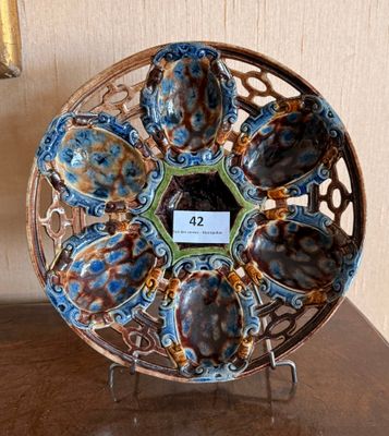 une photo représentant une assiette décorative posée sur un socle, sur une table